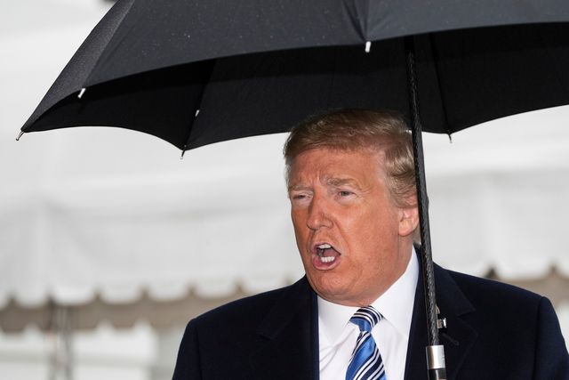 President Trump, under an umbrella and wearing a suit and coat, speaks to reporters on March 28, 2020